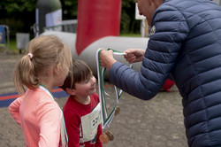 Zwei Kinder stehen nebeneinander und bekommen eine Medaille verliehen.