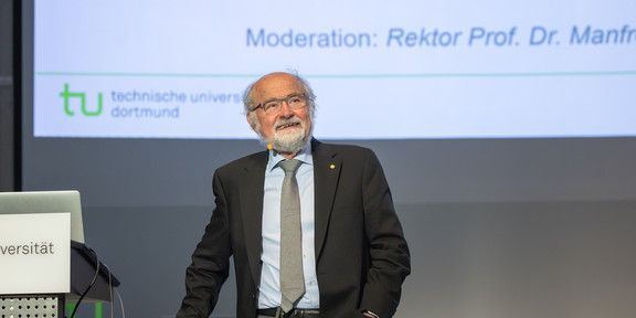 Vortragsreihe „Initialzündung“ Ein Mann im Anzug steht an einem Rednerpult und hält einen Vortrag.