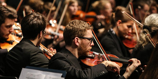 Studentenorchester der TU Dortmund Ein Musiker mit Geige des Studentenorchesters der TU Dortmund im Fokus