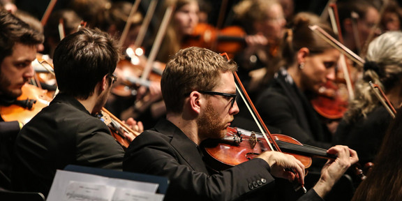 Ein Musiker mit Geige des Studentenorchesters der TU Dortmund im Fokus