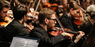 Studentenorchester der TU Dortmund Ein Musiker mit Geige des Studentenorchesters der TU Dortmund im Fokus