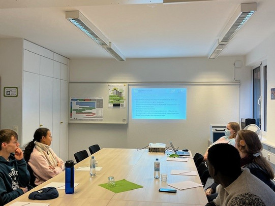 Vier TU-Guides schauen auf die Leinwand und verfolgen die Präsentation.