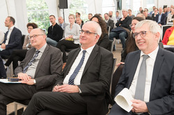 Ein Vortragsraum gefüllt mit Personen, die auf Stühlen sitzen und nach vorne blicken.