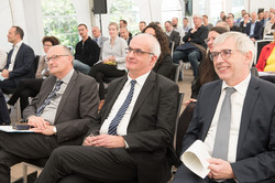 A lecture room filled with people sitting on chairs and looking ahead.