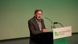 Ein Herr mit Brille und Anzug steht an einem Rednerpult mit der Aufschrift "TU Dortmund".