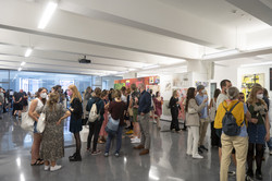 Ausstellung „Rundgang Kunst“ Mehrere Personen stehen in Gruppen zusammen in einer Halle auf einer Kunstausstellung.