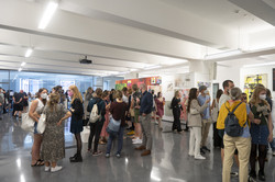 Mehrere Personen stehen in Gruppen zusammen in einer Halle auf einer Kunstausstellung.