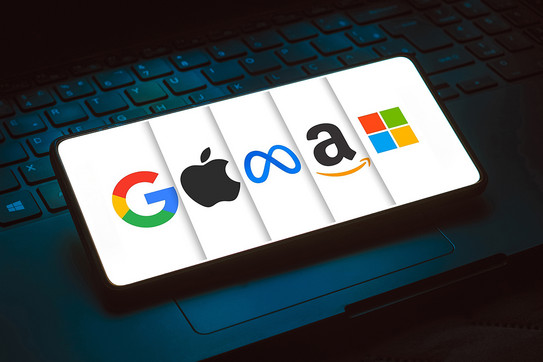 Foto: Ein Smartphone liegt auf einer Tastatur und zeigt die Logos bekannter Technologieunternehmen.