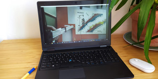 „Affenschuss“-Versuch im Video Ein aufgeklappter Laptop steht auf einem Schreibtisch. Auf dem Bildschirm ist ein physikalischer Versuchsaufbau zu sehen.