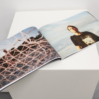 Ein aufgeschlagenes Fotobuch mit zwei Fotographien auf beiden Seiten