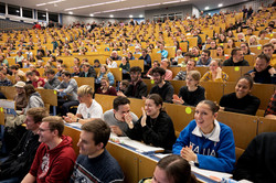 Ein voller Hörsaal mit zuhörenden und lachenden Menschen.