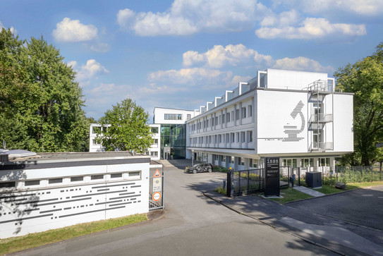 Foto: Das Gebäude des ISAS am Standort in der Dortmunder City an einem sonnigen Tag. Es ist ein L-förmiges weißes Gebäude.