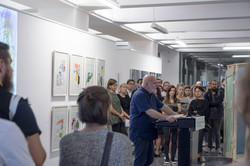 Ein Mann hält am Rednerpult eine Rede vor den Besuchern der Ausstellung