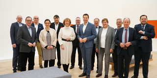 Schick gekleidete Frauen und Männer stehen für ein Gruppenfoto zusammen.