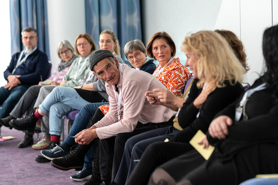 Foto: Mehrere Menschen sitzen in einer Runde.