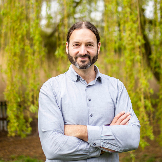 Portrait eines Mannes in hellem Hemd vor einem Baum