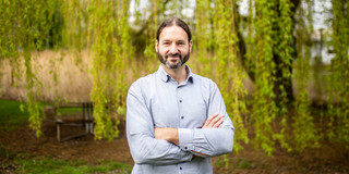 Portrait of a man in a shirt in front of a green tree