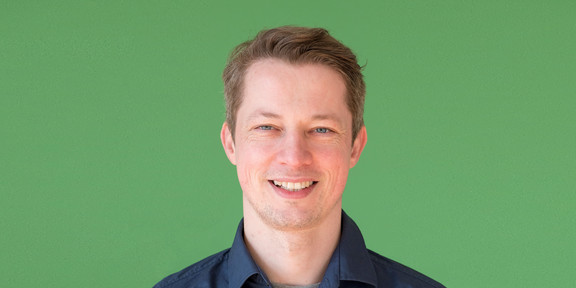 Matthias Kortmann Ein Mann steht vor einem grünen Hintergrund und lächelt.