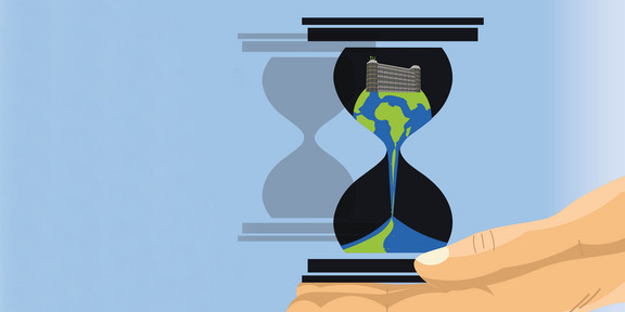Die Erde rieselt durch eine Sanduhr, die von einer Hand gehalten wird.