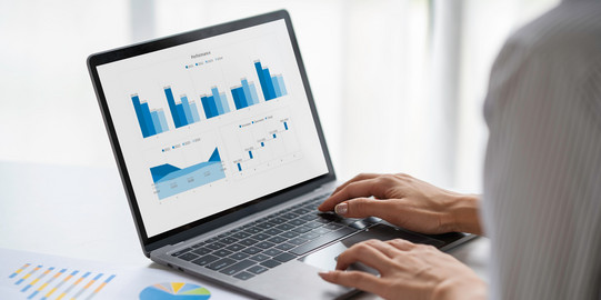 The picture shows a laptop on a table. Several diagrams in shades of blue can be seen on the screen.