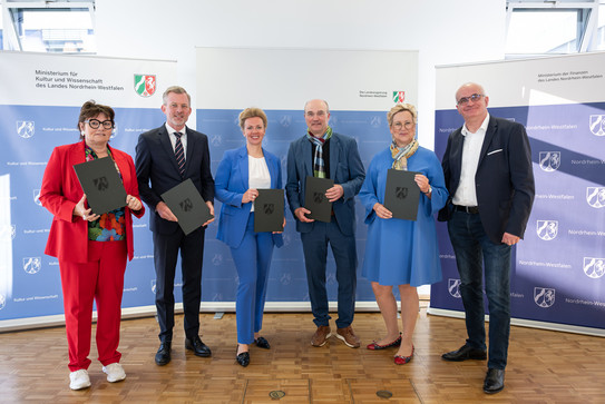 Das Bild zeigt Gabriele Willems, BLB-NRW-Geschäftsführerin, Dr. Dirk Günnewig, Staatssekretär im Ministerium der Finanzen, Ina Brandes, Ministerin für Kultur und Wissenschaft, Prof. Dr. Ulrich Rüdiger, Rektor RWTH Aachen, Prof. Dr. Tamara Appel, Rektorin der FH Dortmund und Prof. Dr. Manfred Bayer, Rektor der TU Dortmund.
