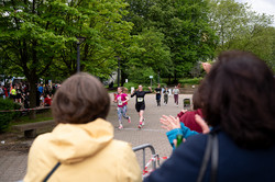 Foto: Zuschauer applaudieren, während Läuferinnen und Läufer auf einer Strecke durch den Campus laufen.