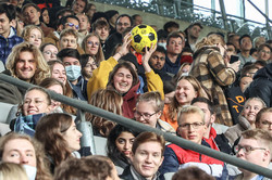 A woman catches a soccer and sits on a stand filled with first-year students.