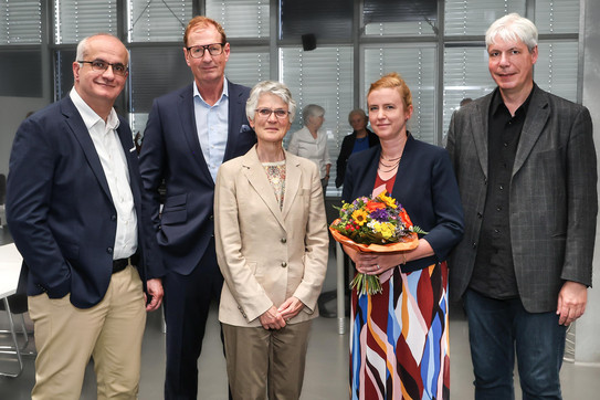 A photo of a group of people with a woman with a bouquet of flowers in the middle.
