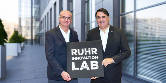Prof. Martin Paul, Rektor der Ruhr-Universität Bochum, und Prof. Manfred Bayer, Rektor der TU Dortmund, mit dem Logo des „Ruhr Innovation Lab“. 