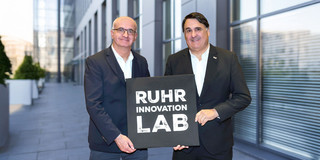 Prof. Martin Paul, Rektor der Ruhr-Universität Bochum, und Prof. Manfred Bayer, Rektor der TU Dortmund, mit dem Logo des „Ruhr Innovation Lab“.