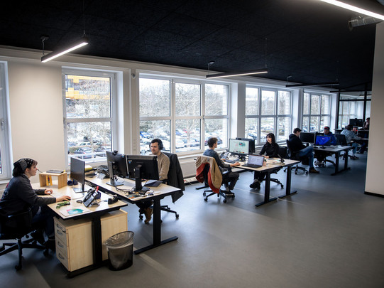 Foto: Mehrere Menschen arbeiten an Schreibtischen mit Computern in einem Büro.