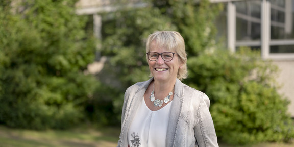 Ulrike Grates Eine Frau lächelt in die Kamera. Im Hintergrund ist eine Wiese zu sehen.