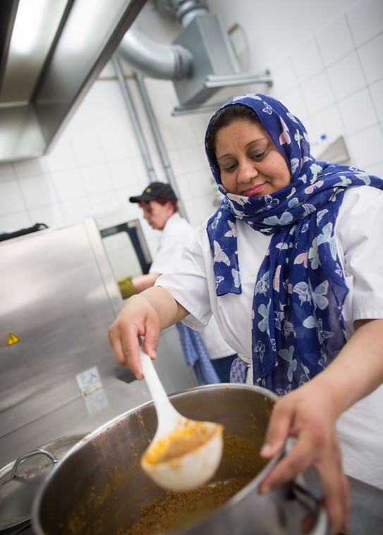 Caritas-Küche In einer Küche rührt eine Frau in einem großen Kochtopf