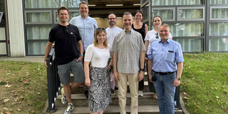 Gruppenfoto mit acht Personen vor einem Gebäude