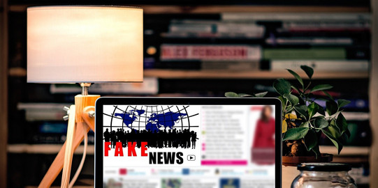 Laptop auf einem Tisch auf dem Fake News zu lesen ist