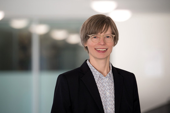 Porträtfoto Prof. Kordula Knaus: Prof. Knaus trägt eine Brille, kurze Haare und eine helle Bluse unter einem Blazer. Sie lächelt in die Kamera.