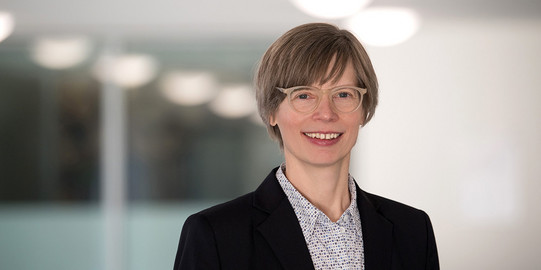 Porträtfoto Prof. Kordula Knaus: Prof. Knaus trägt eine Brille, kurze Haare und eine helle Bluse unter einem Blazer. Sie lächelt in die Kamera.