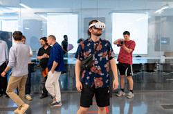 Eine Person mit VR-Brille steht mitten in der Ausstellung. Im Hintergrund laufen weitere Personen.