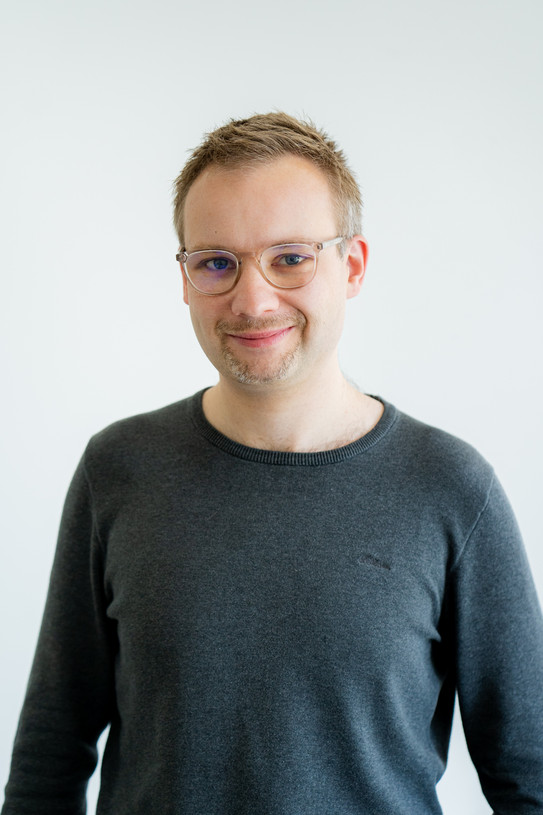 Porträtfoto von Prof. René Westerholt vor einem hellen Hintergrund: Prof. Westerholt trägt eine Brille und ein dunkles Oberteil.