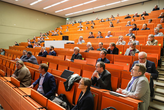 Eröffnung DoBaS Mehrere erwachsene Personen sitzen in einem Hörsaal und haben den Blick nach vorne gerichtet.