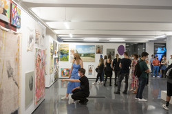 Ausstellung „Rundgang Kunst“ Mehrere Personen stehen in einer Halle einer Kunstausstellung und zwei Personen betrachten ein großes Bild.