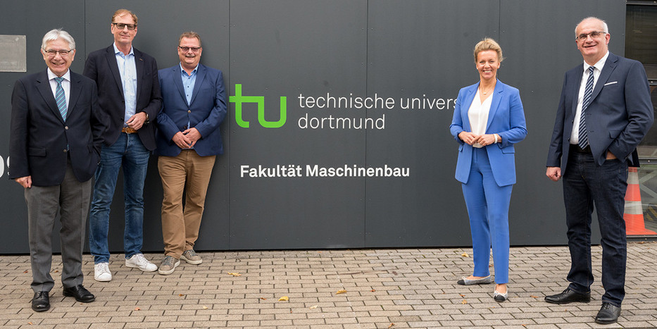 Ina Brandes, Prof. Manfred Bayer, Prof. Gerhard Schembecker, Albrecht Ehlers und Prof. A. Erman Tekkaya stehen vor einer Mauer, auf der das Logo der TU Dortmund und der Schriftzug "Fakultät Maschinenbau" zu sehen ist.