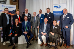 Gruppenfoto: Ein Foto von zwei Frauen und neun Männern in Anzügen, die sitzend und stehend für ein Gruppenfoto posieren.