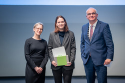 Auf dem Foto sind drei Personen nach der Übergabe des Forschungspreises zu sehen.