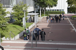 Mehrere Personen laufen auf dem Campus Süd in Richtung H-Bahn.