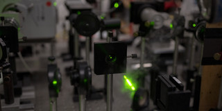 There are several devices in a laboratory and green laser beams are shining.