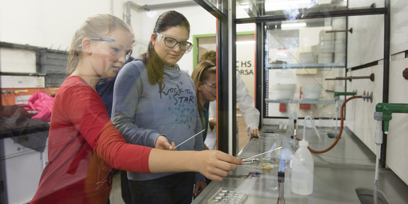 Zwei Mädchen mit Schutzbrille führen ein Experiment im Labor durch.