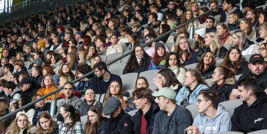 Eine Tribüne in einem Fußballstadion ist gefüllt mit Erstsemesterstudierenden.