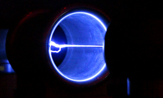 Bläulich leuchtender Lichtbogen in einem Rohr.