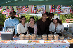 Gruppenfoto von Studierenden, die an einem Stand malaysische Gerichte verkaufen.